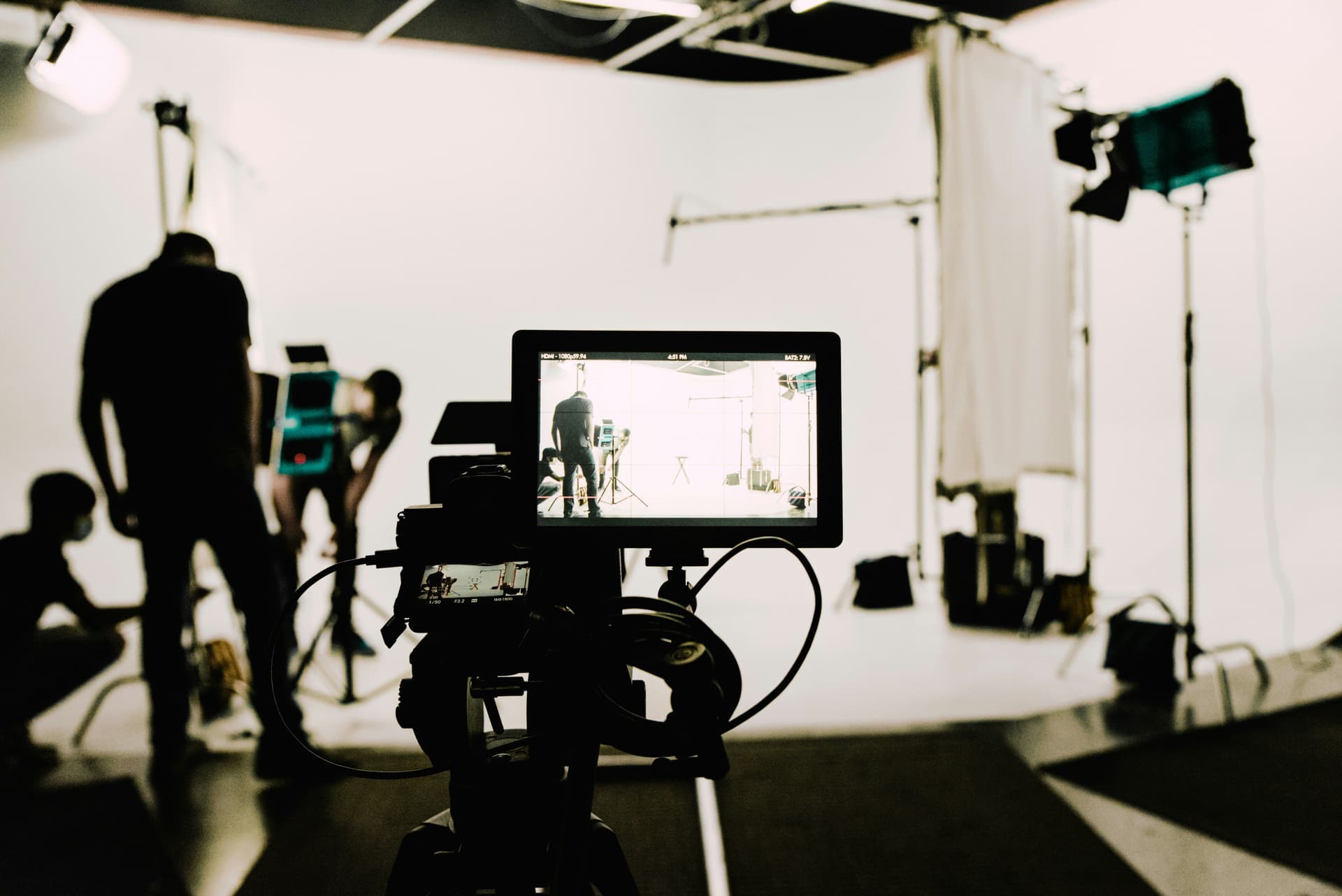 Silhouette of a film crew in a studio as seen through a camera's display.