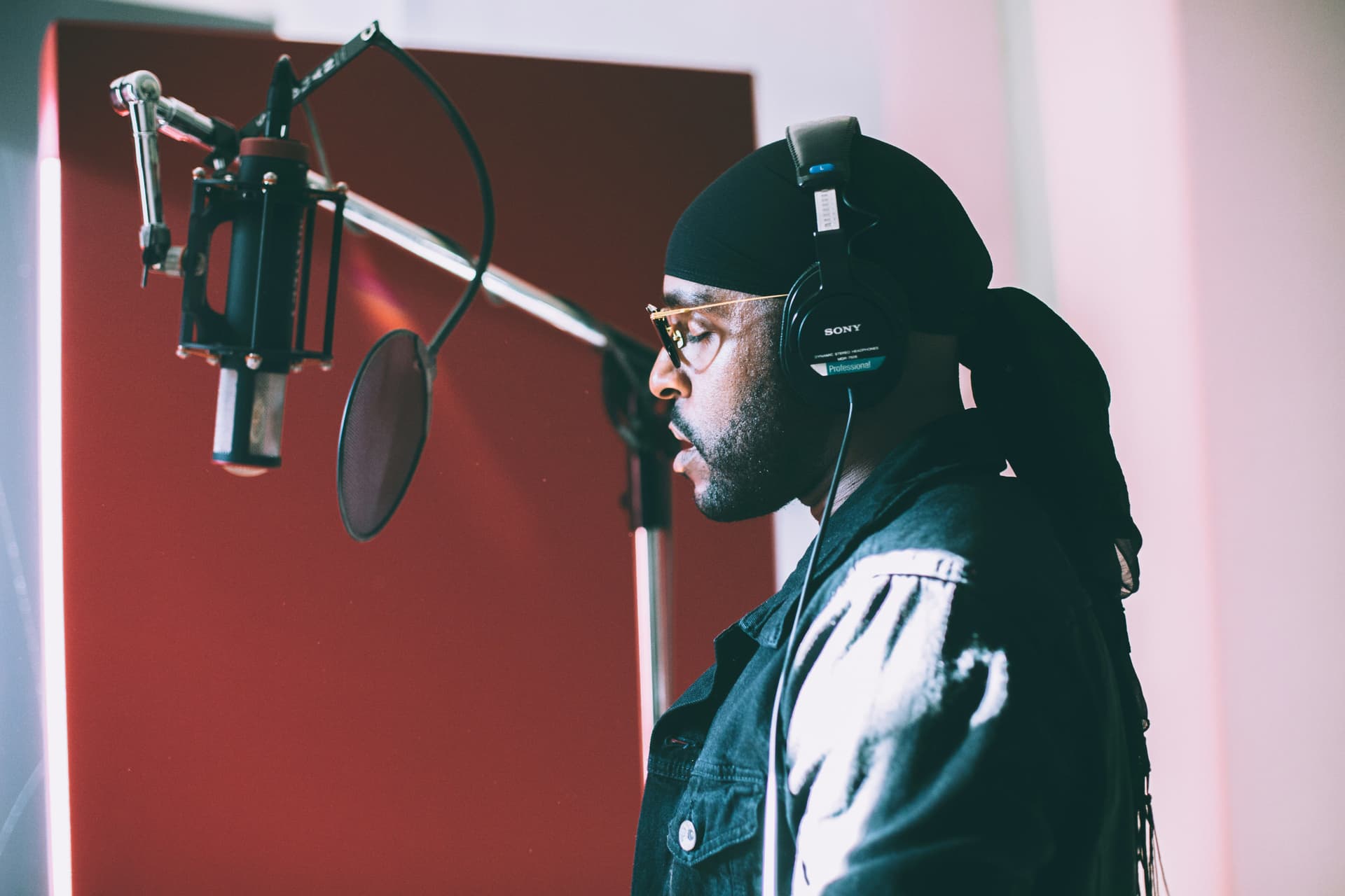 Person in a recording studio with a microphone and wearing headphones.